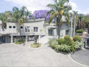 a large white house with palm trees and flowers at Silva Villa in Bedfordview