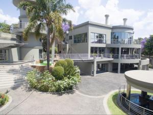 a large white house with a palm tree at Silva Villa in Bedfordview