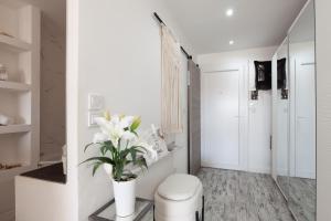 ein weißer Flur mit einer Toilette und einer Vase mit Blumen in der Unterkunft Appartement 4 personnes proche port in Sanary-sur-Mer