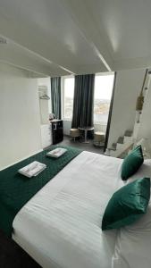 Un dormitorio con una gran cama blanca con almohadas verdes. en Reef Lodge, en Newquay