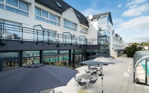 a patio with tables and umbrellas in front of a building at Brit Hôtel De L'océan in Concarneau