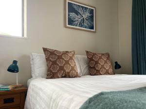 a bed with two pillows and a picture on the wall at Deluxe Seaside Flat easy access in Westward Ho