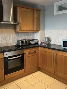 a kitchen with wooden cabinets and a stove top oven at Deluxe Seaside Flat easy access in Westward Ho +7 photos