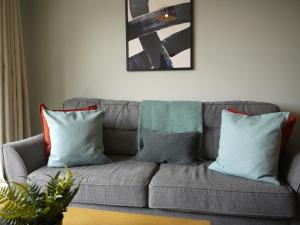 a gray couch with pillows in a living room at Deluxe Seaside Flat easy access in Westward Ho