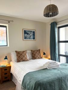 a bedroom with a white bed with a blue blanket at Deluxe Seaside Flat easy access in Westward Ho