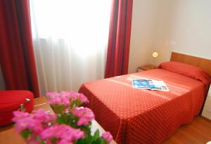 - une chambre avec un lit et une table fleurie dans l'établissement Camere Delfini, à Palmanova