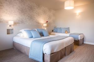 a hotel room with two beds with blue pillows at Villa Odette in Deauville