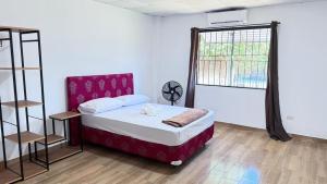 a bedroom with a bed with a red headboard and a window at Casa kuarahy in Asuncion