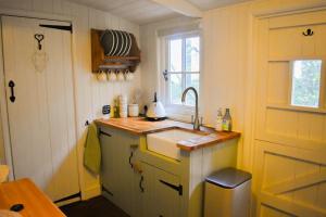 a small kitchen with a sink and a window at Shepherd Hut in the woods in Clothall