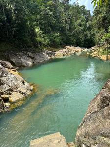 a river with green water and rocks and trees at Cabaña con fogata BBQ y ríos cerro azul in Los Altos de Cerro Azul