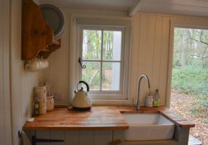 Una encimera de cocina con un fregadero y una ventana. en Shepherd Hut in the woods, 