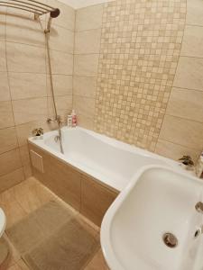 een badkamer met een bad, een toilet en een wastafel bij Tulipán Apartman in Békéscsaba