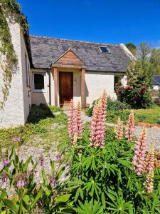 ein Haus mit einem Blumenstrauß davor in der Unterkunft Highland River Cottage with Hot Tub in Evanton