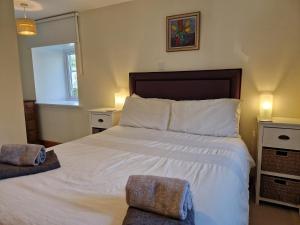 1 Schlafzimmer mit einem großen weißen Bett mit 2 Stühlen in der Unterkunft Highland River Cottage with Hot Tub in Evanton