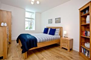 a bedroom with a bed with blue pillows and a book shelf at 9 At The Beach, Torcross in Torcross