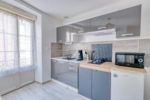 una cocina con armarios azules y TV en una encimera en Le Confort du Soir - T2 - Lagnieu, en Lagnieu