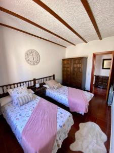 two beds in a room with a clock on the wall at Finca roxana in Elda