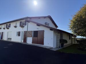 a white house with brown doors and a driveway at Agueramonde in Mouguerre