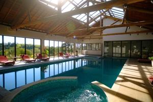 an indoor swimming pool with chairs and a large building at Hotel Chalés Capitanias in Águas de Lindoia