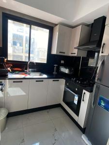 eine kleine Küche mit weißen Schränken und einem Kühlschrank in der Unterkunft Charming apartment in Ariana