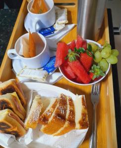 a table with a plate of food and a bowl of fruit at Suites Vento Solar Buzios in Búzios