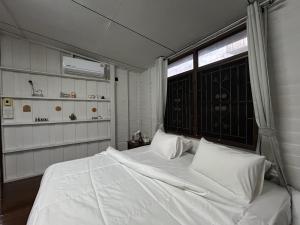 ein Schlafzimmer mit einem großen weißen Bett mit einem Fenster in der Unterkunft Wooden Friend House in Krabi