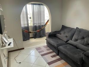 um sofá preto numa sala de estar com um espelho em Apartamento aconchegante próximo a praia em Ilhéus