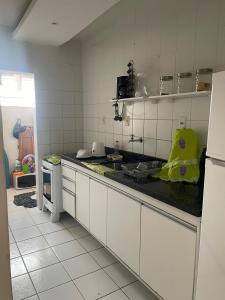 uma cozinha com armários brancos e uma bancada preta em Apartamento aconchegante próximo a praia em Ilhéus mais 4 fotografias