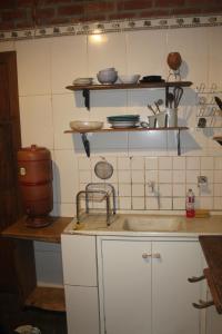 a kitchen with a sink and shelves with dishes at Suíte Oriente Vale do Capão Refúgio acolhedor com vista para montanha & pet friendly in Caeté-Açu