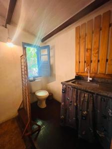 a bathroom with a toilet and a sink and a window at Tropicália Hostel e Pousada in Itacaré