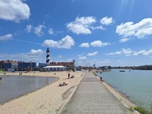 a beach with people on the sand and a lighthouse at Appartement cosy et lumineux Gravelines centre la gravelinoise 2 in Gravelines