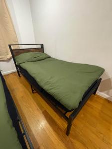 un letto con piumone verde su un pavimento in legno di Union Square Studio with Kitchen -Shared Bathroom a New York