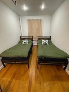 2 letti in una piccola camera con pavimenti in legno di Union Square Studio with Kitchen -Shared Bathroom a New York Altre 14 foto