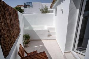 Un pequeño balcón con paredes blancas y un banco de madera. en Hotel Boutique Maram-Adults Only, en Vejer de la Frontera