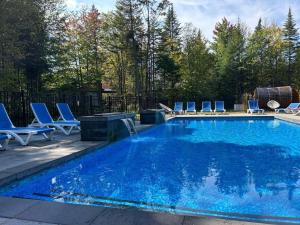 a swimming pool with chairs and a table and a swimming pool at Chalet Arianna in Pont-Rouge