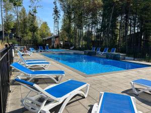 a group of lounge chairs and a swimming pool at Chalet Arianna in Pont-Rouge