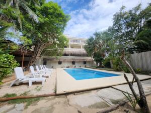 a swimming pool with white chairs and a building at MK BEACH Playa Del Carmen in Playa del Carmen