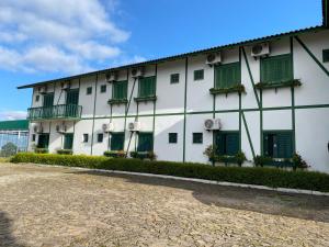 a large white building with green shuttered windows at Letto Hotel Candeeiro da Serra in Salvador do Sul