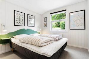 a bedroom with a bed with a green headboard and two windows at LF16121-Farso-Bjarkesvej-11 in Farsø