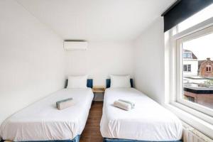 two beds in a room with a window at The Alkmaar Family House in Alkmaar