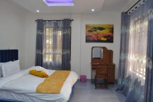 ein Schlafzimmer mit einem Bett, einem Schreibtisch und einem Spiegel in der Unterkunft White House II in Naivasha