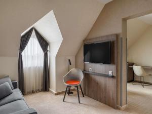 a living room with a couch and a television at Mercure Budapest Korona in Budapest