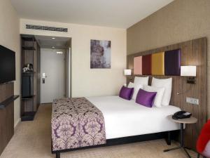 a bedroom with a large white bed with purple pillows at Mercure Budapest Korona in Budapest +97 photos