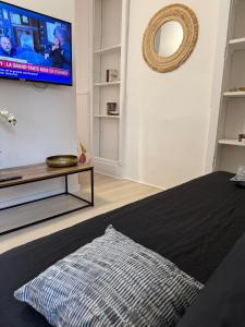 een woonkamer met een bed en een flatscreen-tv bij SWEET HOME Votre havre de paix au cœur d'Epernon in Épernon