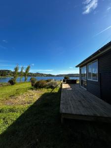 a house with a wooden deck next to a body of water at Casadelaisla-Rilan in Rilán