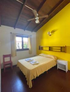 ein Schlafzimmer mit einem Bett mit gelber Wand in der Unterkunft Chill hotel in Villa Gesell