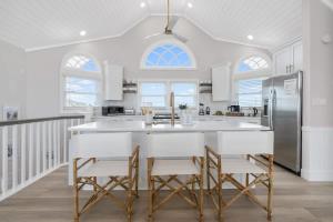 a kitchen with a large white island with stools at Elegant Updated Oceanfront Home with Pool & Hot Tub in Waves