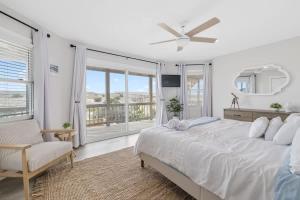 a white bedroom with a bed and a large window at Elegant Updated Oceanfront Home with Pool & Hot Tub in Waves
