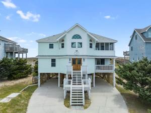 a blue house with stairs leading up to it at Elegant Updated Oceanfront Home with Pool & Hot Tub in Waves