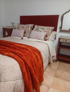a bedroom with a bed with an orange blanket at Casa Rural en San Carlos del Valle- Doña Gumersinda in San Carlos del Valle